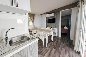 Une chambre d’hôtel compacte dotée d’une kitchenette, d’un coin repas, d’un téléviseur fixé au mur et d’un espace nuit séparé.