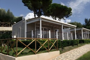 A row of modern, single-story buildings with balconies, surrounded by greenery and trees. - Sea View - 40 Parallelo - Deluxe 3, Marina di Camerota, Italy (Marina di Camerota)
