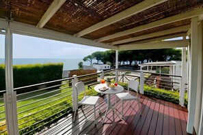 A balcony with a table and chairs, overlooking a body of water and greenery. - Sea View - 40 Parallelo - Deluxe 3, Marina di Camerota, Italy (Marina di Camerota)