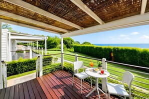A covered outdoor area with a wooden deck, white chairs, and a table. - Sea View - 40 Parallelo - Deluxe 3, Marina di Camerota, Italy (Marina di Camerota)