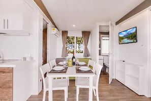 A modern, well-lit dining area with a table set for four, a kitchen with white cabinetry, and a television mounted on the wall. - Sea View - 40 Parallelo - Deluxe 2, Marina di Camerota, Italy (Marina di Camerota)