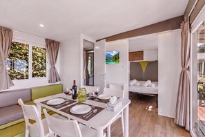 Habitació senzilla amb zona de menjador, sofà, llit i televisió.