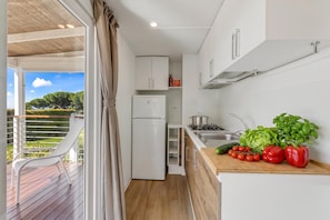 Une cuisine compacte équipée d’un réfrigérateur, d’une cuisinière et d’un plan de travail en bois où sont disposés des légumes.