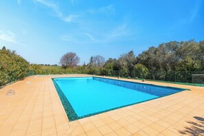 A rectangular swimming pool with a tiled deck, surrounded by trees and a fence. - Oleandro Apartment Relax Near The Sea, Cecina, Italy (Cecina)