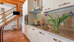 Ett kök med vita skåp, en rostfri köksfläkt, en diskho och en vas med blommor.