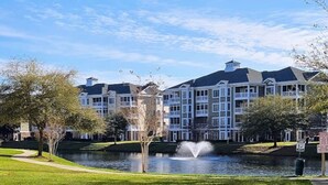 A building with a large lawn, a fountain, and a body of water. - Sweet Magnolias | Beach Escape Near Top Courses (Myrtle Beach)