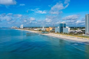 A coastal cityscape with a beach, a large Ferris wheel, and high-rise buildings. - Sweet Magnolias | Beach Escape Near Top Courses (Myrtle Beach)