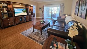 A living room with a television, a leather sofa, a coffee table, and a ceiling fan. - Sweet Magnolias | Beach Escape Near Top Courses (Myrtle Beach)