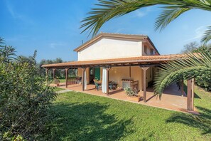 A house with a covered patio, a green door, and a small garden. - Eucalipto Apartment with Shared Pool, Near The Sea, Cecina, Italy (Cecina)