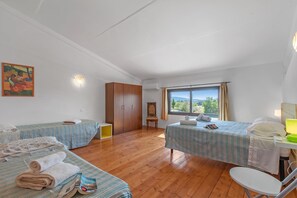 A room with two beds, a wooden wardrobe, a chair, a table with a lamp, and a window with a view. - Eucalipto Apartment with Shared Pool, Near The Sea, Cecina, Italy (Cecina)