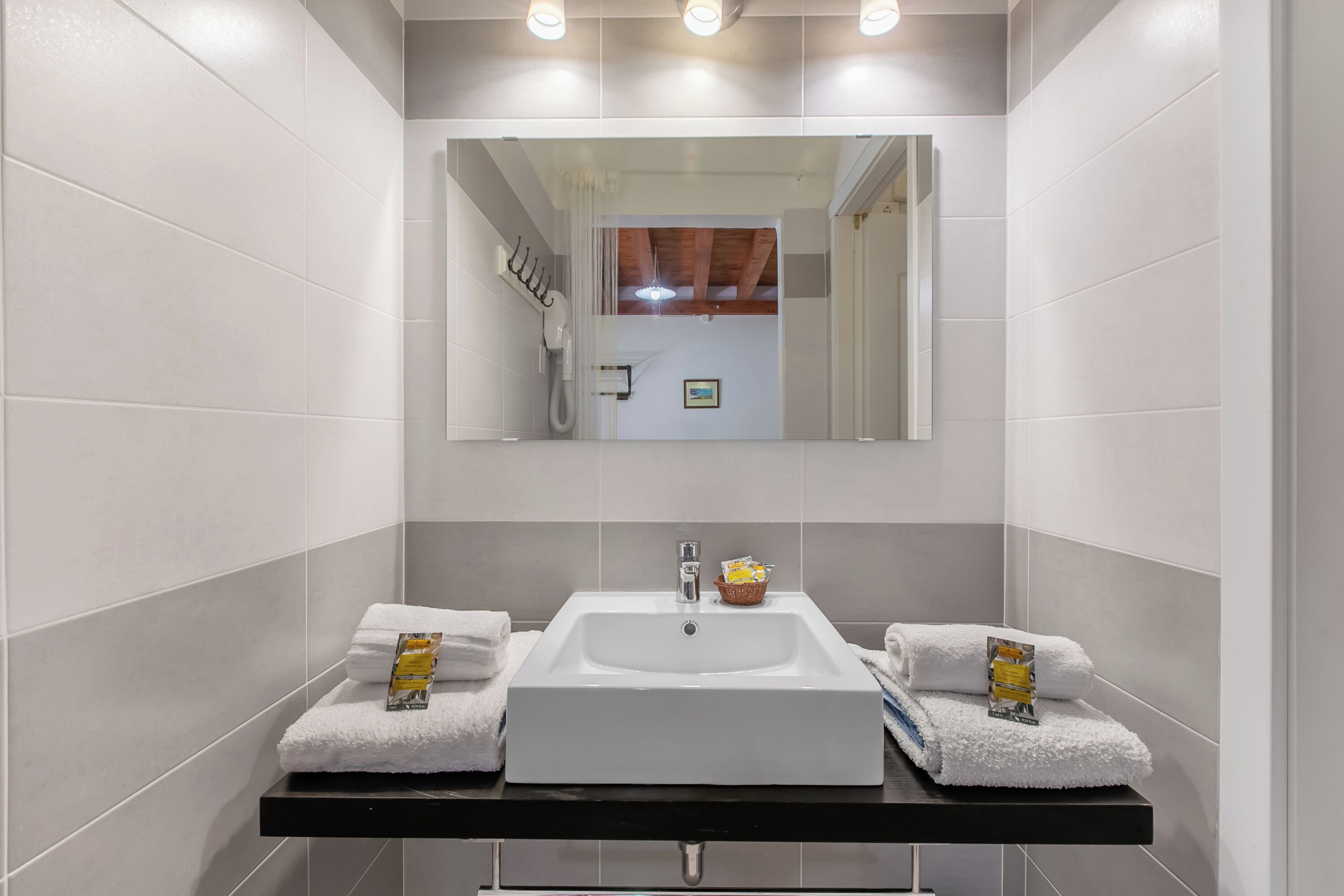 Un baño moderno con un lavamanos grande, dos toalleros y un espejo.
