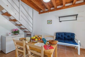 A dining area with a wooden table, chairs, a sofa, and a staircase. - Vigna Apartment Relax Near The Sea, Cecina, Italy (Cecina)