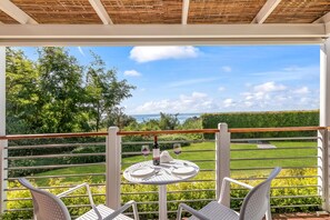 A balcony with a table set for two, overlooking a garden and a view of the sea. - Sea View - 40 Parallelo - Deluxe 1, Marina di Camerota, Italy (Marina di Camerota)
