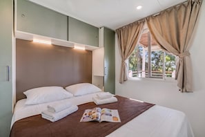A hotel room with a bed, pillows, a magazine, and a window with curtains. - Sea View - 40 Parallelo - Deluxe 1, Marina di Camerota, Italy (Marina di Camerota)
