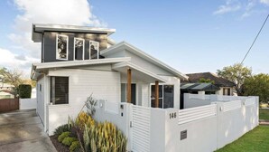 A modern two-story house with a white exterior, a gated driveway, and a well-maintained front yard with plants. - Lakeshore Serenity @ Warners Bay (Warners Bay)