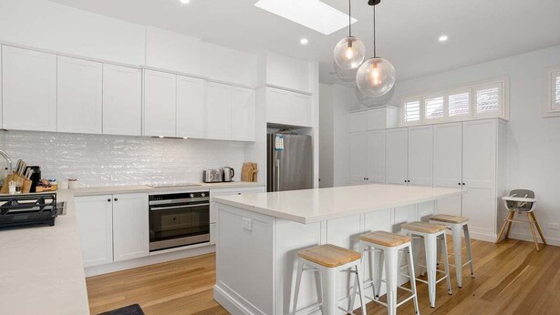 A modern kitchen with white cabinetry, a central island with stools, a stainless steel refrigerator, and a pendant light. - Lakeshore Serenity @ Warners Bay (Warners Bay)