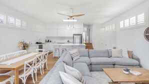 A modern interior with a dining area, a gray sectional sofa, and a kitchen in the background. - Lakeshore Serenity @ Warners Bay (Warners Bay)