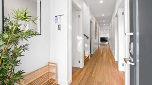 A hallway with a wooden bench, a potted plant, and a door with a sign. - Lakeshore Serenity @ Warners Bay (Warners Bay)