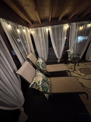 A covered outdoor seating area with cushioned chairs and a table, draped with sheer curtains and string lights. - The Healing Haven / Peaceful Retreat in Philadelphia / 3BR, 4BA Townhome (Philadelphia)