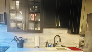 Una cocina moderna con armarios oscuros, un refrigerador de acero inoxidable, lavavajillas integrado y una encimera de mármol.