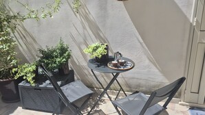 Un petit espace extérieur aménagé avec une table, des chaises et des plantes en pot.