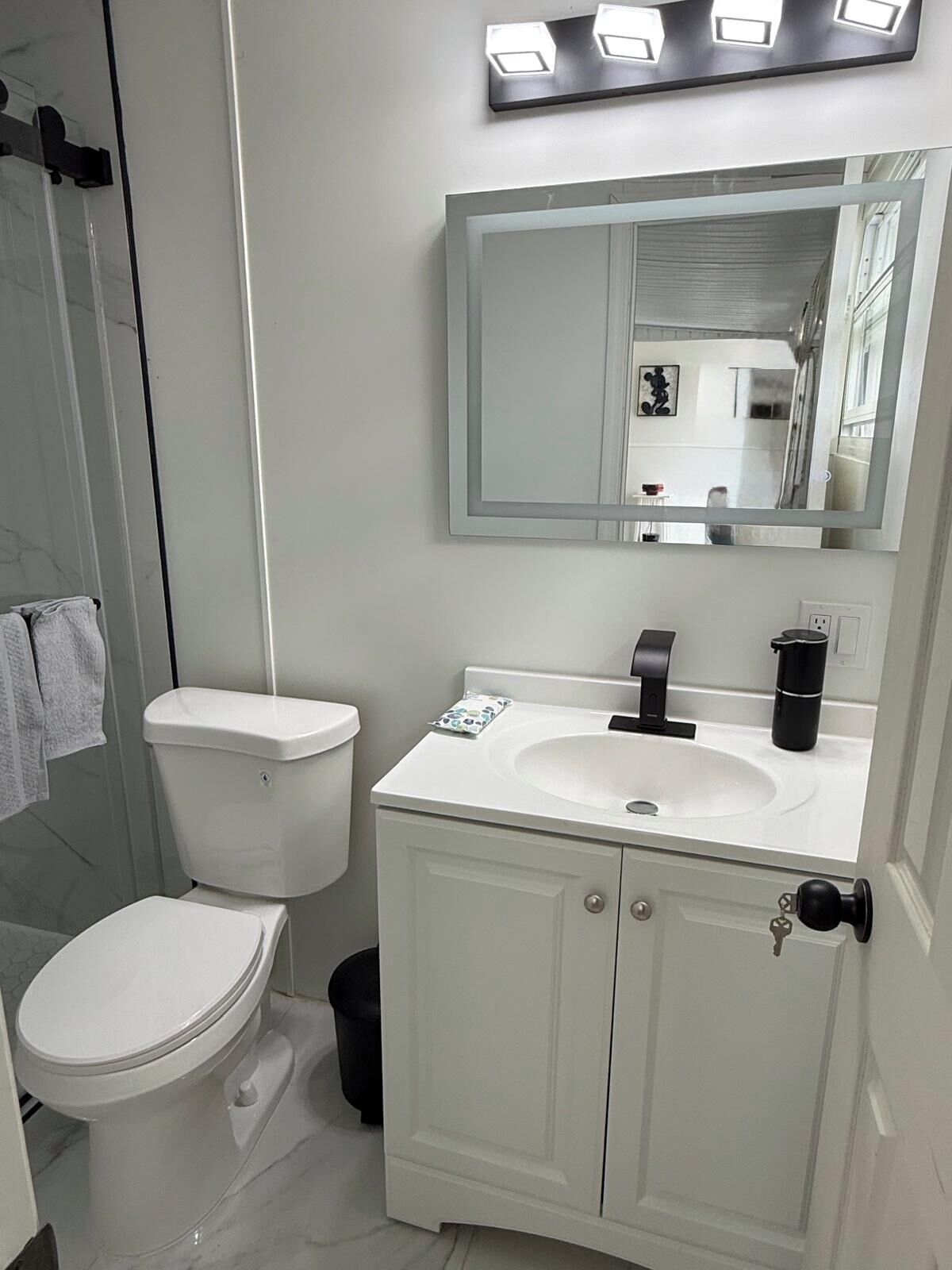 Ein Badezimmer mit Toilette, Waschbecken, Spiegel und Schrank.