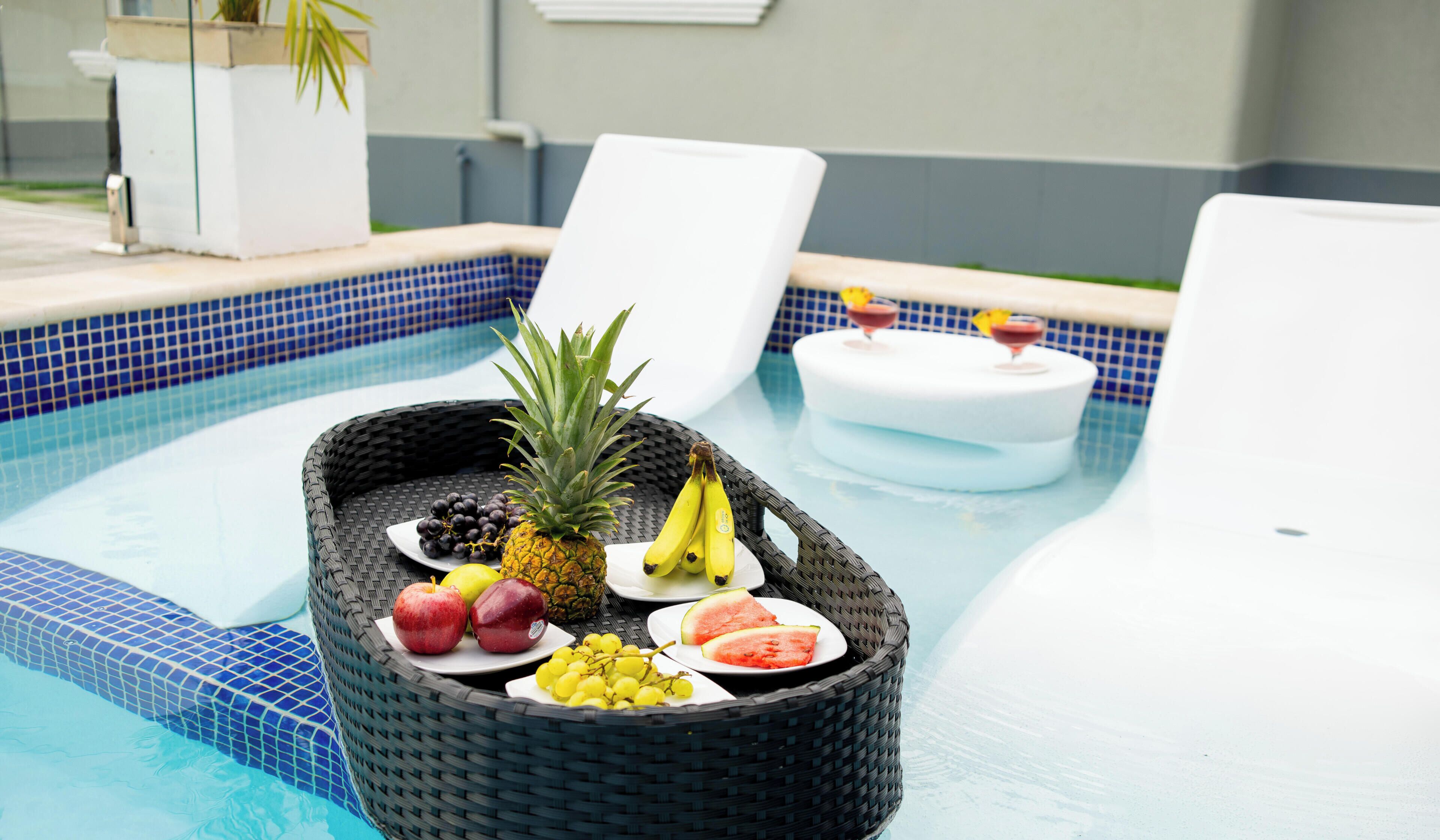 Poolområde med frugtkurv, liggestole og jacuzzi.
