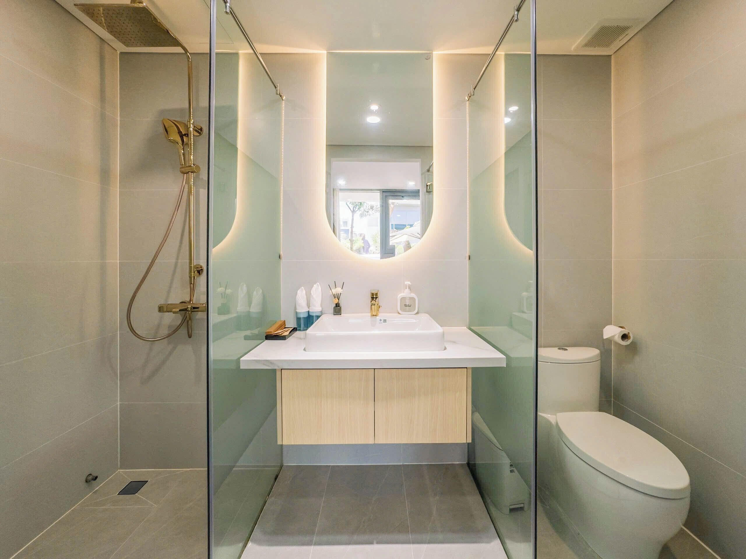 A modern bathroom with a glass-enclosed shower, a white sink with a wooden cabinet, and a toilet.