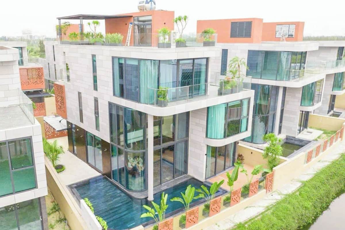 Un edificio residencial de varios pisos con balcones, ventanas amplias y una piscina.