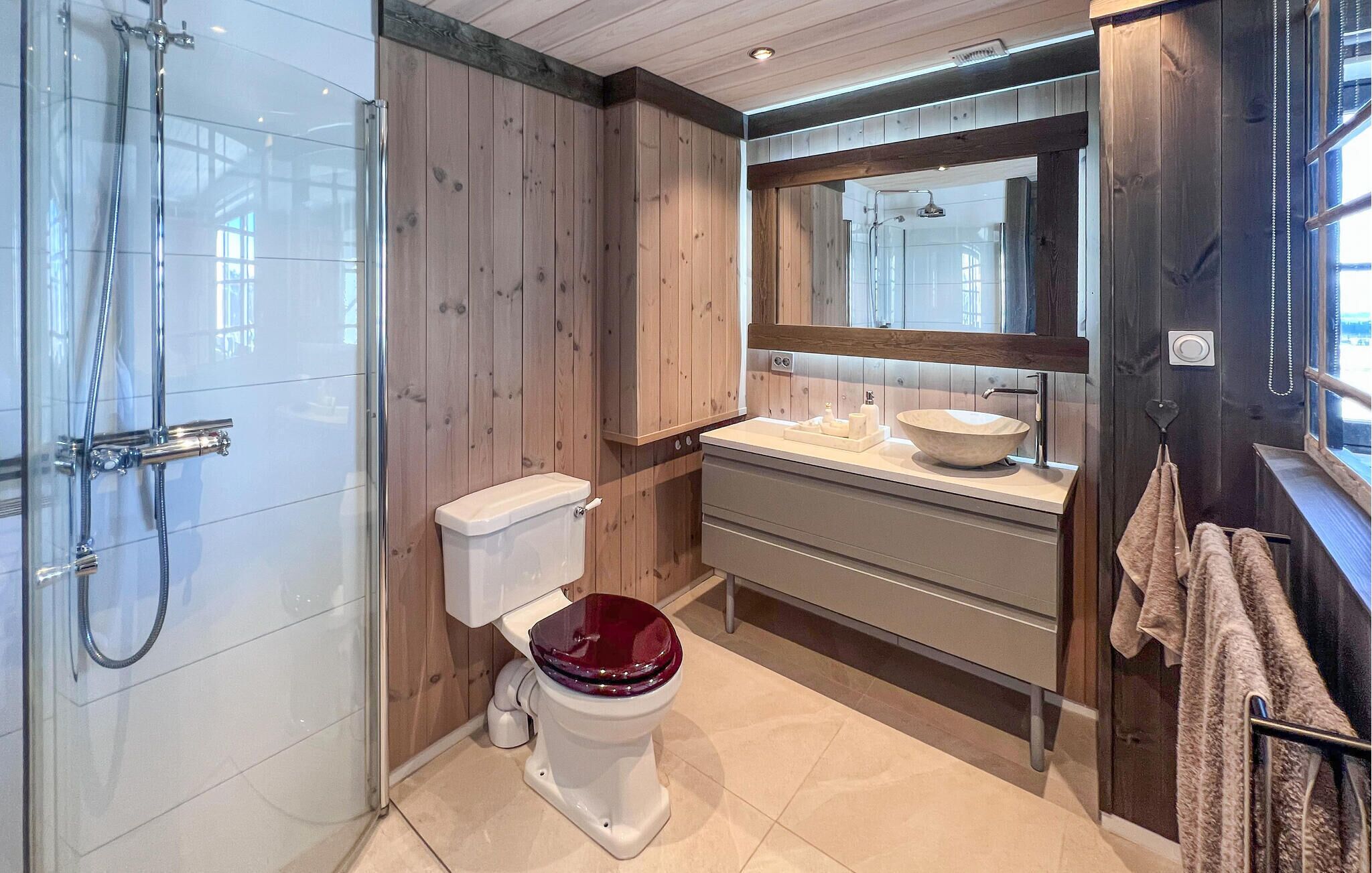 A bathroom with a shower, toilet, sink, and mirror.