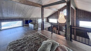 Ein großzügiges Loft mit hohen Decken, einer Holzvertäfelung, einem großen, flauschigen Teppich und einer Hängeleuchte.