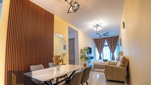 A modern living room with a sofa, a dining table with chairs, a ceiling fan, and a large window with curtains. - Legasi Kampung Baru By Skylivia (Kuala Lumpur)