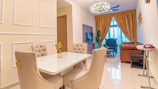 A dining area with a white table, beige upholstered chairs, and a chandelier. - Legasi Kampung Baru By Skylivia (Kuala Lumpur)
