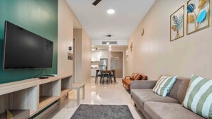 A living room with a flat-screen TV, a sofa, a coffee table, and a dining area with a table and chairs. - Legasi Kampung Baru By Skylivia (Kuala Lumpur)