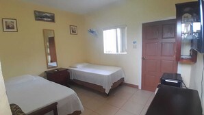 Une chambre avec deux lits, un bureau, une chaise, un miroir, une fenêtre avec des rideaux et une porte.