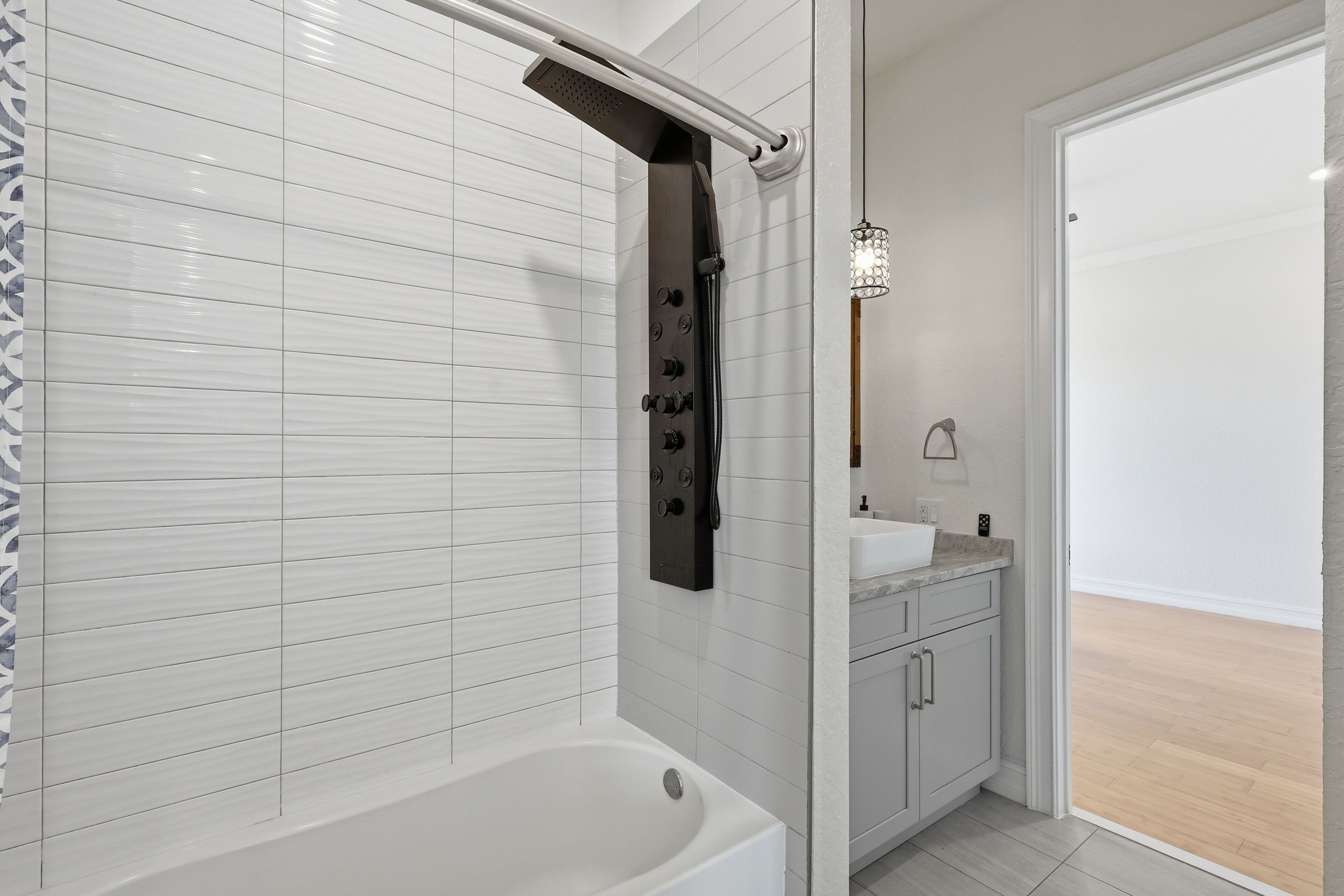 Une salle de bain moderne équipée d’une baignoire, d’une douche avec commandes, d’un lavabo et d’un meuble de rangement.