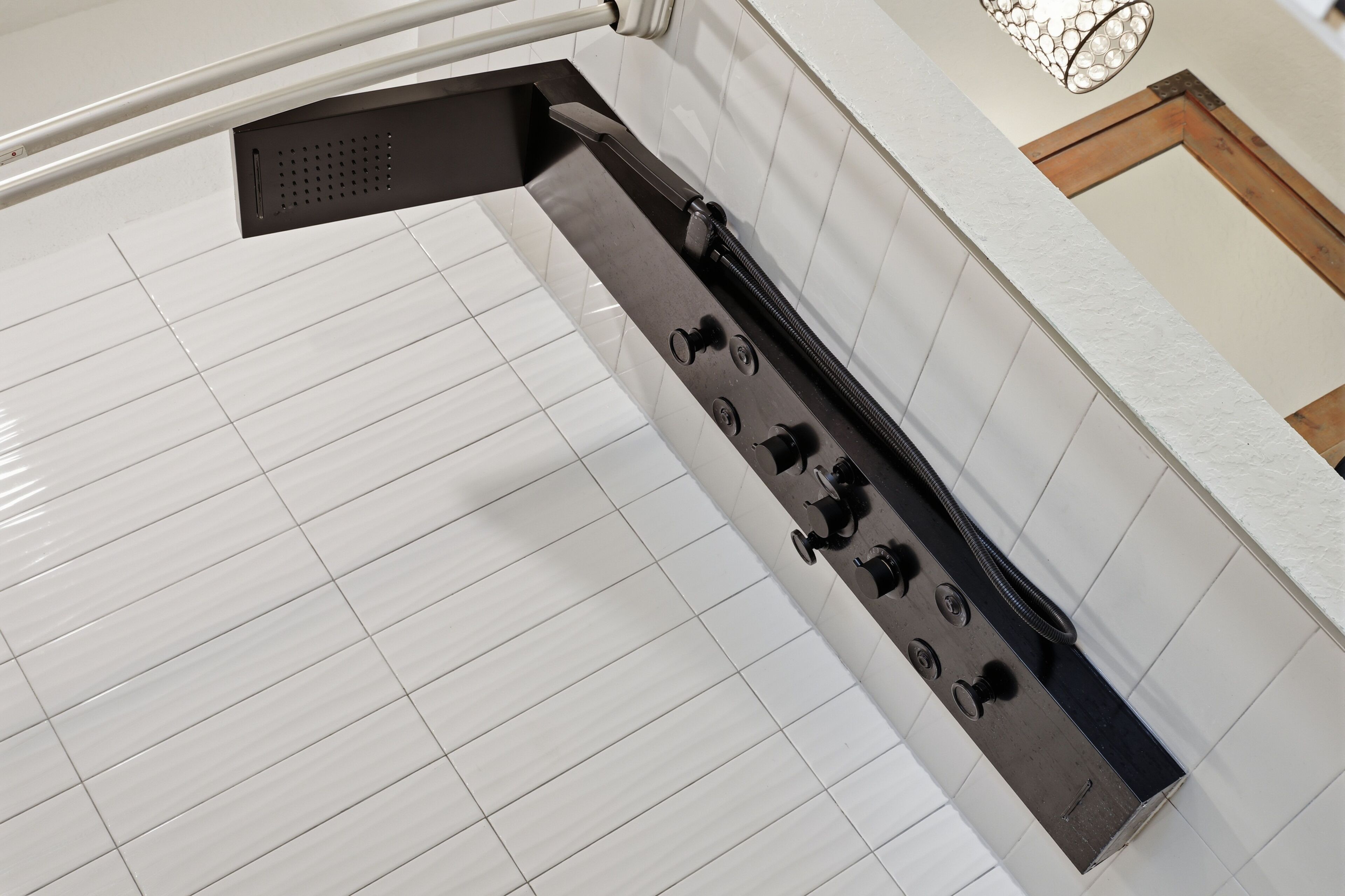 Uma cozinha com piso de azulejos brancos, coifa de aço inoxidável e bancada branca.