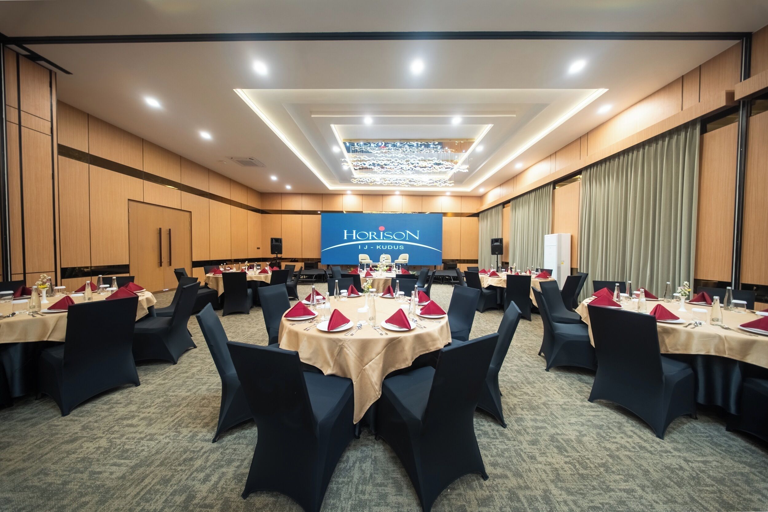 A conference room with round tables, black chairs, and a chandelier.