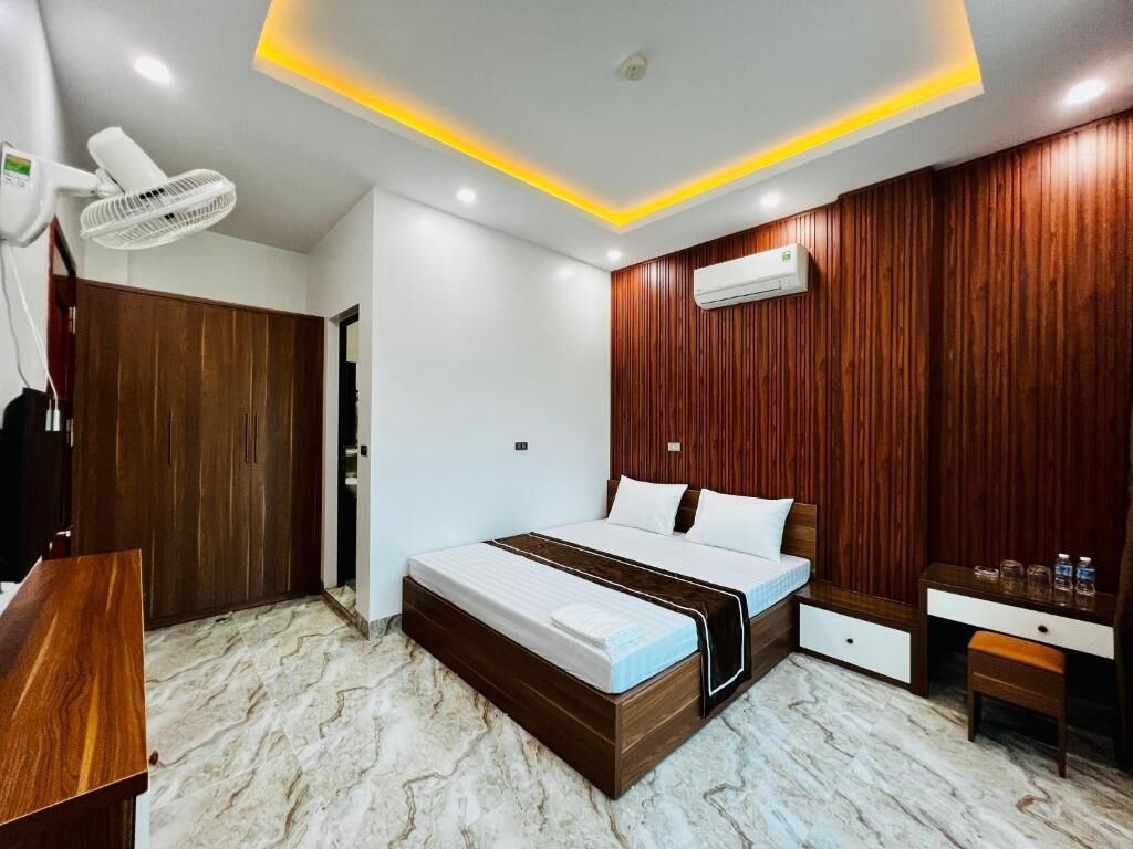 Quarto com cama, mesa de cabeceira e escrivaninha com cadeira.