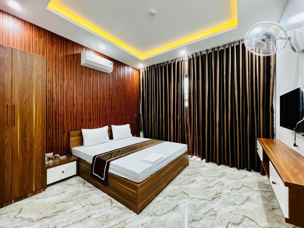 A modern bedroom with a wooden bed frame, a bedside table, an air conditioning unit, and a ceiling fan.