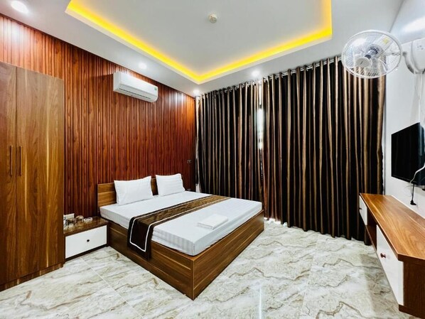 A modern bedroom with a wooden bed frame, a bedside table, an air conditioning unit, and a ceiling fan. - THANH HONG HOTEL (Thanh Sen)