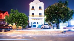 Un hôtel à la façade blanche, doté de balcons et d’une enseigne indiquant « HÔTEL THANH HONG 2 ».