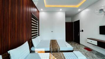 A hotel room with a bed, a TV, a fan, and a wooden wall.