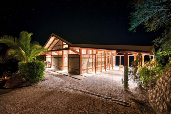 A modern house with a covered patio, stone walls, and a gravel driveway. - The Ledge - Infinity Pool Overlooking the Ocean & Mountains (Chinampas)