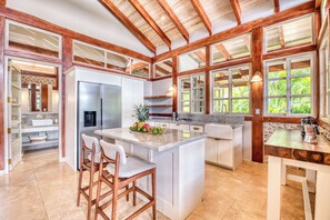 A spacious kitchen with a central island, wooden beams, and large windows. - The Ledge - Infinity Pool Overlooking the Ocean & Mountains (Chinampas)