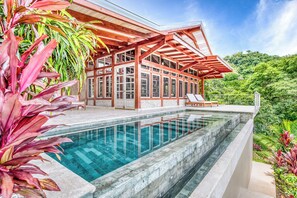 A modern house with a swimming pool, wooden deck, and lush greenery. - The Ledge - Infinity Pool Overlooking the Ocean & Mountains (Chinampas)