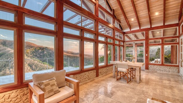 A spacious room with large windows, a dining area, and a seating area with a view of the outdoors. - Villa 4 - The Ledge - Infinity Pool Overlooking the Ocean & Mountains (Chinampas)