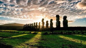 Una hilera de estatuas de piedra en un campo cubierto de césped, bajo un cielo nublado.