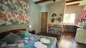Un dormitorio con cama, escritorio y silla, además de una cocina con armarios y refrigerador.