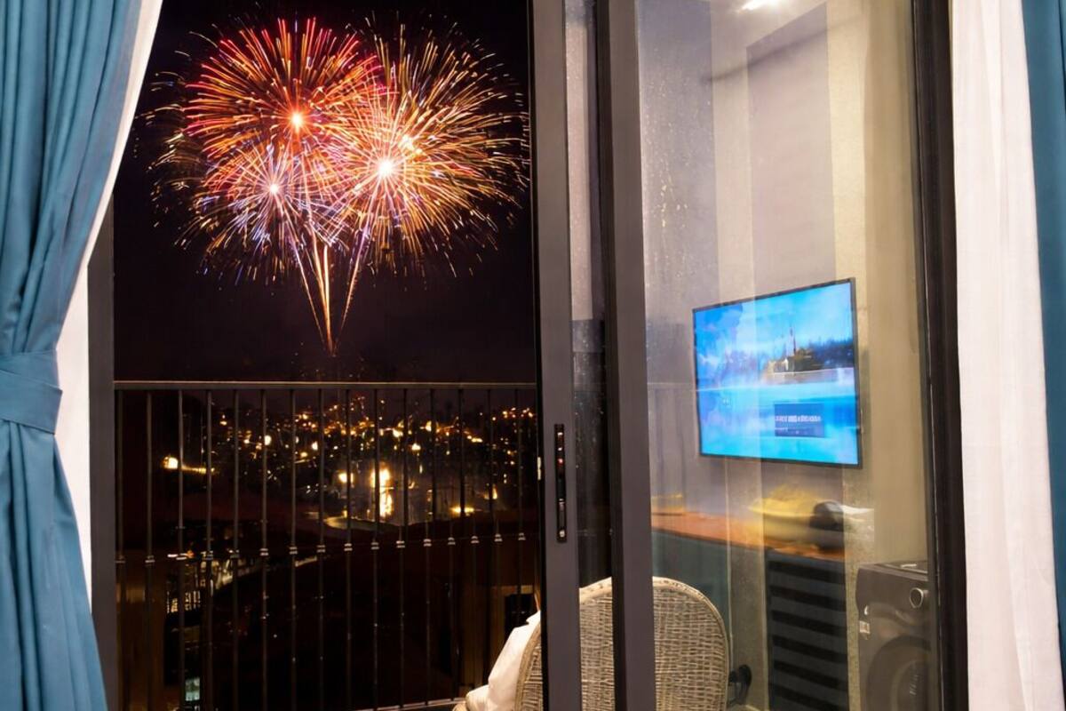 Ein Balkon mit Blick auf die Stadt, einem Fernseher und einem Korbstuhl.